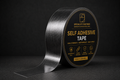 A roll of self-adhesive tape with a brushed metallic silver surface, shown on a dark background. The circular label is black with gold text and icons, and a strip of the tape is unrolled to the left.
